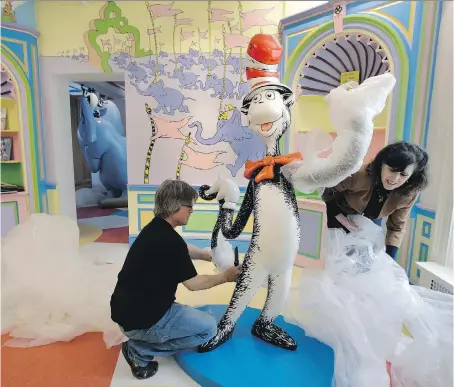  ?? PHOTOS: STEVEN SENNE/THE ASSOCIATED PRESS ?? John and Kay Simpson unwrap a Cat in the Hat statue at the new Amazing World of Dr. Seuss museum.