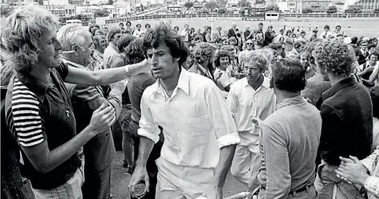  ?? PHOTOS: STUFF ?? Richard Hadlee, already with a celebrator­y glass in hand, leaves the Basin Reserve among a throng of delighted New Zealand fans. Captain Mark Burgess is behind Hadlee.