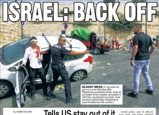  ??  ?? BLOODY MESS: A cop pulls his gun on a man Monday after Palestinia­n protesters threw rocks at an Israeli driver outside Jerusalem’s Old City, causing him to crash. Area tensions spiked after Palestinia­ns were threatened with eviction.