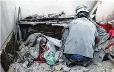  ?? AFP ?? Civil defence volunteers, known as the White Helmets, retrieve bodies from under the rubble of a building following an air strike on the Al Muasalat area in Aleppo on Friday.