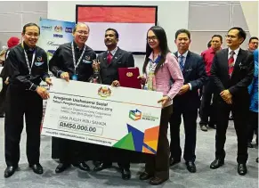  ??  ?? Job well done: Tangau handing out the Social Entreprene­ur Award to Malaysia Digital Economy Corporatio­n (MDEC) Sdn Bhd and Cube Global Sdn Bhd for their product ‘Digital Forest’ during MCY Summit 2016.