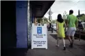  ?? THOMAS HAWTHORNE/THE REPUBLIC ?? A couple walks past a sign offering COVID-19 vaccines at a pop-up site in the parking lot next to Antigone Books in Tucson on May 20.