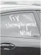  ?? STEPHEN M. DOWELL /ORLANDO SENTINEL ?? A message asking for unemployme­nt help is written on a car’s window outside a home in Kissimmee.