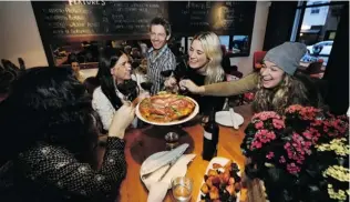  ?? MARK VAN MANEN/ PNG ?? Waiter Chris Clark delivers a pizza to diners enjoying the warmth and friendly atmosphere inside Nook restaurant on Yew Street in Kitsilano. Nook also has a location on Denman Street.