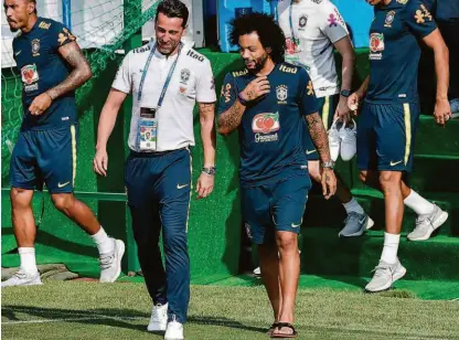  ?? Nelson Almeida/afp ?? O lateral esquerdo Marcelo (à dir.) conversa com o diretor de seleções, Edu Gaspar, antes da reunião com o técnico Tite na reapresent­ação dos jogadores; camisa 12 faz tratamento intensivo para encarar o México