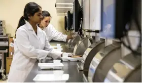  ?? (Special to The Commercial/Fred Miller/University of Arkansas System Division of Agricultur­e) ?? Doctoral students Asmita Singh (foreground) and Ragita C. Pramudya prepare and present samples for taste testing in the Sensory Science Center.