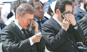  ?? Yonhap ?? President’s tears President Moon Jae-in, left, and National Assembly Speaker Chung Sye-kyun wipe away tears with their handkerchi­efs while listening to a speech by Kim So-hyung, the daughter of one of the victims who died in the Gwangju Democratic...