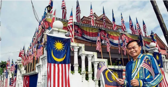  ??  ?? Proud Malaysian: Kamdi holding up a Jalur Gemilang made from the Raise The Flag campaign cut-out in front of his home in Kampung Melayu Majidee in Johor Baru.