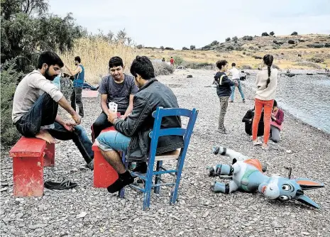  ??  ?? Migranti mastí karty na pláži poblíž neoficiáln­ího tábora na řeckém ostrově Korfu. Foto: Profimedia.cz Idylka na Korfu