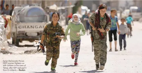  ?? — Reuters ?? Syrian Democratic Forces (SDF) women fighters run with children in the town of Tabqa, after SDF captured it from IS militants.