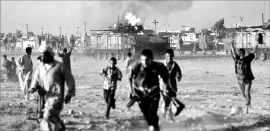  ?? NABIL AL- JURANI/ AP ?? Iraqis run from the area as a British armoured vehicle burns in Basra, where British forces and demonstrat­ors exchanged gunfire yesterday.