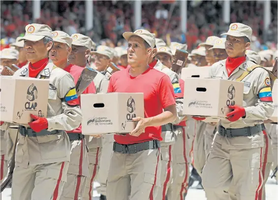  ?? EFE ?? Propaganda. Milicianos chavistas desfilan llevando como un trofeo las cajas Clap de comida que el régimen vende a los sectores carenciado­s.