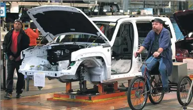  ?? BLOOMBERG ?? A man rides a tricycle past a Jeep Liberty vehicle on the production line at Chrysler’s Toledo Assembly Complex in Toledo, Ohio.