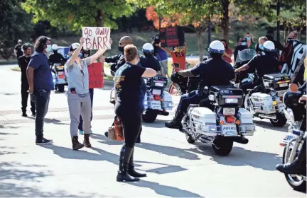  ?? PHOTOS BY MAX GERSH/THE COMMERCIAL APPEAL ?? Protesters hold signs as U.S. Attorney General William Barr’s motorcade leaves the Memphis Police Department’s Ridgeway Station on Oct. 21, 2020.