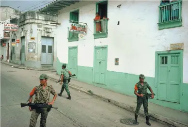  ??  ?? Government troops enforcing a daytime curfew after a massacre in San Vicente de Chucurí, Colombia, 1988