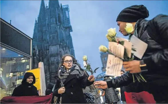  ?? MAJA HITIJ / EFE ?? Un miembro de la Asociación de Jóvenes Germano-Tunecinos entregando ayer una rosa blanca con una nota a una joven en Colonia