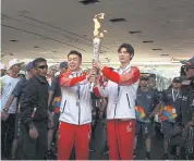  ??  ?? IT’S ALL YOURS: Chinese runners hand over the torch during the last torch relay in Jakarta ahead of the opening ceremony of the 2018 Asian Games.