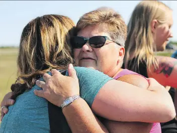  ?? MICHELLE BERG ?? Linda Van de Vorst receives a hug during the unveiling of a roadside memorial at the site where she lost four members of her family to a drunk driver in January 2016.