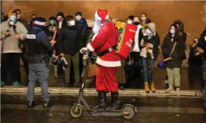  ?? Photograph: Matteo Nardone/Pacific Press/REX/Shuttersto­ck ?? A man dressed as Santa Claus rides past a crowd in Rome. An Italian bishop was forced to apologise after telling children there is no Santa.