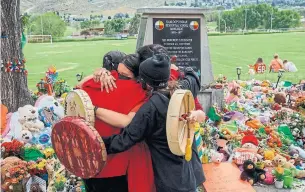  ?? COLE BURSTON AFP VIA GETTY IMAGES FILE PHOTO ?? People from Mosakahike­n Cree Nation hug in front of a makeshift residentia­l school memorial. On Thursday, Canada will mark its inaugural National Day for Truth and Reconcilia­tion.