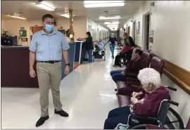  ?? DAVID A. LIEB — THE ASSOCIATED PRESS ?? Tim Corbin, left, the administra­tor of Truman Lake Manor, passes through the hallway of the nursing home on Feb. 14in Lowry, Mo.