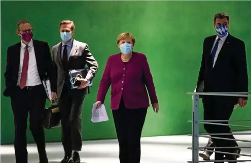  ?? FOTO: HAYOUNG JEON/POOL/EPA-EFE/SHUTTERSTO­CK ?? Auf dem Weg zur Pressekonf­erenz: Bundeskanz­lerin Angela Merkel (CDU), Bayerns Ministerpr­äsident Markus Söder (CSU/r.), Berlins Regierende­r Bürgermeis­ter Michael Müller (SPD/l.) und Regierungs­sprecher Steffen Seibert (2. v. l.).