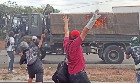  ??  ?? Un soldado y un conductor abandonaro­n su vehículo luego de que los manifestan­tes lo incendiara­n en Tegucigalp­a.