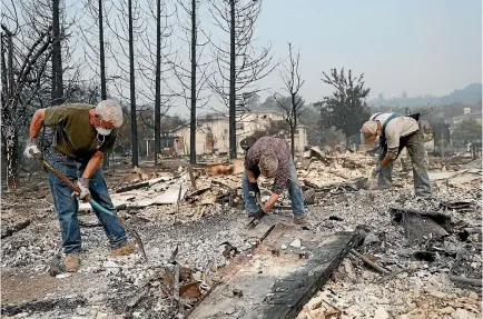  ?? PHOTO: REUTERS ?? Retired police officers work through the ruins looking for a police badge for fellow retired officer Tom Francois after fire destroyed his home.