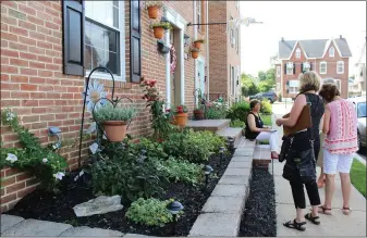  ??  ?? People stand outside a Boyertown residence and view the planted area as they judge it for the Home Garden Contest.