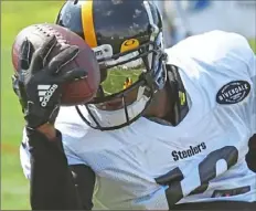  ?? Peter Diana/ Post- Gazette ?? HEADS AND TALES JuJu Smith- Schuster makes one of the catches of camp so far on Wednesday, a one- handed snag against his helmet at Saint Vincent College.