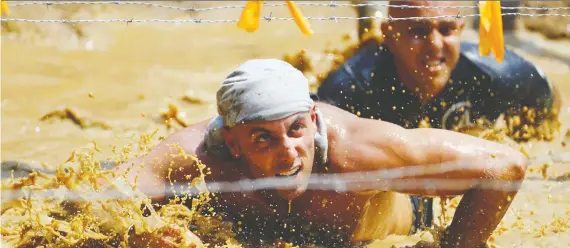  ?? BRUCE BENNETT/GETTY IMAGES ?? Tough Mudder competitio­ns have participan­ts crawling under wires, plunging into ice cold water and jumping over walls as they trek through nature.