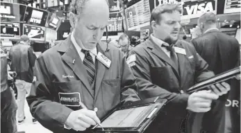  ?? RICHARD DREW, AP ?? Gordon Charlop, left, works with fellow traders at the New York Stock Exchange on Tuesday. The Dow, S&P 500 and Nasdaq all finished higher Tuesday, while the Russell 2000 was flat.