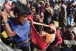  ?? — AFP ?? Rohingya refugees carry a woman after crossing the Naf River as they flee violence in Myanmar to reach Bangladesh in Palongkhal­i near Ukhia on Monday. The UN has said that 537,000 Rohingya have arrived in Bangladesh over the last seven weeks.