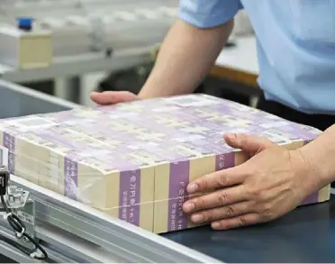  ?? ?? Slow move: an employee inspects wrapped stacks of newly-designed 10,000 yen banknotes at the National Printing Bureau Tokyo plant. The yen has slumped more than 7% this year, driven by the yawning gap between us and Japanese bond yields. — Bloomberg