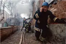  ?? Evgeniy Maloletka/Associated Press ?? A rescue worker speaks on the phone while his team puts out a fire in a house that was shelled by Russian forces.