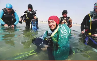  ?? Reuters ?? Abrar Abu Abdullah, a Saudi female diver, smiles while wearing the Saudi national flag over her shoulders as she prepares to dive at the Half Moon Beach open-water dive site in Dhahran, Saudi Arabia, on September 15.