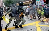  ?? — AFP ?? Riot police (L) use pepper spray at journalist­s (R) as protesters gather for a rally against a new national security law in Hong Kong on Wednesday, on the 23rd anniversar­y of the city’s handover from Britain to China.