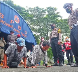  ?? AHMAD KHUSAINI/JAWA POS ?? AYO PUSH-UP DULU: Petugas satgas Covid-19 menghukum pengendara yang tidak memakai masker saat memasuki Surabaya di checkpoint Suramadu kemarin (11/1). Pada masa PPKM, pengawasan di checkpoint perbatasan Surabaya diperketat dengan menambah personel satgas Covid-19.