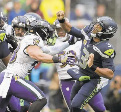  ?? JOHN FROSCHAUER/AP ?? Seahawks quarterbac­k Russell Wilson (3) takes a hit from Ravens linebacker L.J. Fort, left, during the first half Sunday in Seattle.