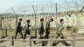  ?? AP PHOTO, ABOVE; AP FILE PHOTO, BELOW ?? DIPLOMACY: South Korean soldiers, above, pass a fence yesterday decorated with ribbons calling for reunificat­ion of the Koreas. North Korean leader Kim Jong Un, below, is set to meet South Korean President Moon Jae-in in a summit soon.