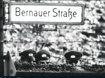  ??  ?? East German policemen peer over the Berlin Wall in 1961. At least 140 people were killed or died at the wall before it was pulled down almost three decades later Under surveillan­ce