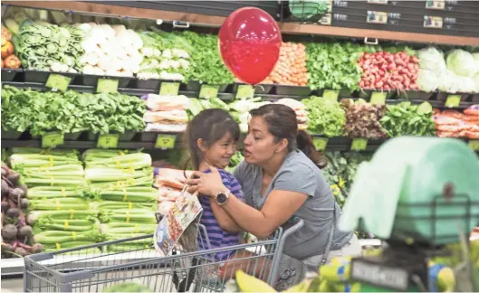  ?? NICK OZA/THE REPUBLIC ?? Leonela Rodas kisses her 4-year-old daughter, Ruth, while they shop during the recent grand opening of a Sprouts Farmers Market in Mesa. The store was the company’s 250th to open in the United States.