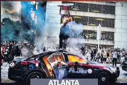  ??  ?? ATLANTA
BLAZING ANGER Police car on fire near the city’s CNN Center