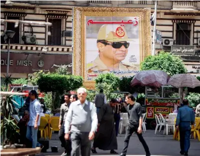  ?? AFP ?? Egyptians walk past a poster bearing a portrait of Abdel Fattah Al Sisi in Cairo. —