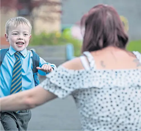  ?? Picture Andrew Cawley ?? Jack Sneddon finishes his first day at Our Lady of the Missions primary school near Glasgow and is greeted by his mum Fiona