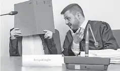  ??  ?? Defendant Jennifer W (left) hides her face behind a folder and sits next to her lawyer Ali Aydin as she waits at court for the opening of her trial in Munich, southern Germany. — AFP photo