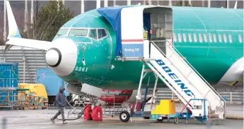  ?? — AFP photo ?? A person walks past an unpainted Boeing 737-8 MAX parked at Renton Municipal Airport adjacent to Boeing’s factory in Renton, Washington. Boeing employees working on 737 MAX production paused their work for a day to discuss ways of improving safety practices.