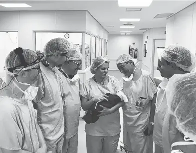  ?? HOSPITAL DAS CLÌNICAS DA FMUSP ?? Doctors at a hospital in Sao Paulo hold a baby girl born to a mother who received a uterus from a deceased donor.