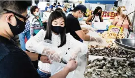  ?? PHOTOS BY SCOTT MCINTYRE The New York Times ?? Wendy Liu and Yang Zhao fill their bags with shrimp at the Plaza Seafood Market.