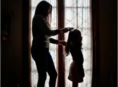  ?? ESTEBAN FELIX/AP ?? Monica Flores combs her daughter’s hair at their home in Santiago, Chile. Flores was questioned by Chilean police at the airport because the records didn’t match: she had left on holidays abroad with a son and returned to the country with a daughter...